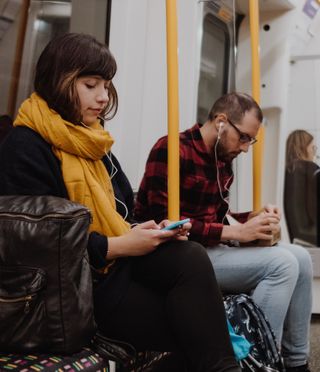 Une femme assise dans un métro écoute l'édition Express de la Bible en 1 an